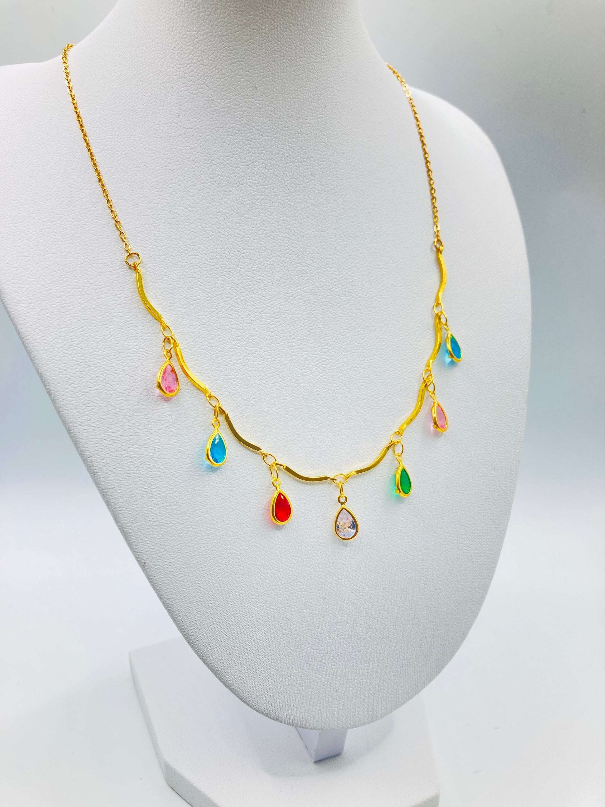 Gold necklace with colorful teardrop-shaped pendants on a mannequin bust.